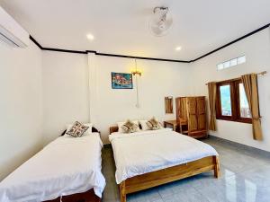 a bedroom with two beds and a window at phoulisack2 guesthouse in Nongkhiaw