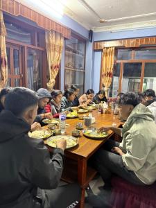 a group of people sitting at a table eating food at Hotel River View in Syābru Bensi