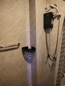 a bathroom with a shower with a toilet and a phone at Nord House Laoag in Laoag +17 photos