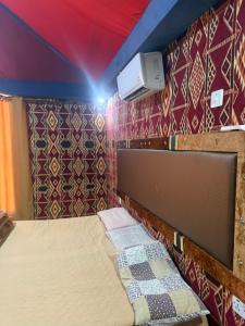 a small bed in a room with colorful walls at Rayyan Bedouin life camp in Wadi Rum