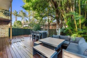 a patio with a couch and a table and chairs at Treetops Sunrise Beach in Byron Bay
