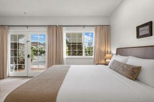 a bedroom with a large white bed and sliding glass doors at Bella Notte by the Beach in Santa Cruz