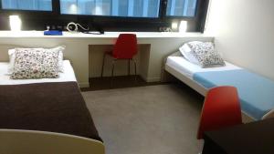 ロルモンにあるStudy Hôtel Bordeaux Lormontのベッド2台と赤い椅子が備わる小さな客室です。