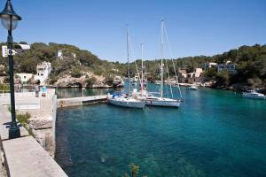 two boats docked in a river with blue water at Apartamentos Llevant in Cala Figuera