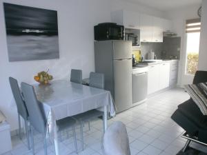 a kitchen with a white table with chairs and a refrigerator at La Pomme de Mer in Saint-Gildas-de-Rhuys