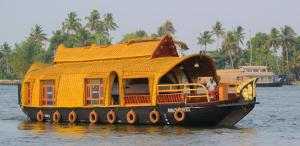 a large yellow house boat in the water at Traditional Houseboat in Alleppey