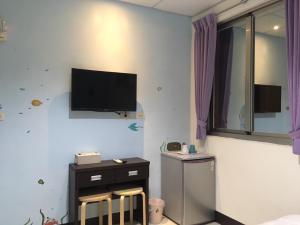 a bedroom with a tv on the wall and two chairs at HFun Hotel in Kaohsiung