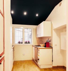 una cucina con armadi bianchi e soffitto nero di Paglia House of 17Century in Trastevere a Roma