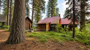 a log cabin in the woods with a red roof at McCall Lakehouse Private Dock Beach & Grill in McCall