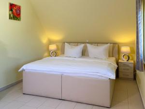 a bedroom with a large white bed with two lamps at Ferienhaus Seegras in Groß Kirr