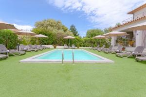 a swimming pool with chairs and umbrellas in a yard at Le dune relax con cucina & piscina in San Teodoro