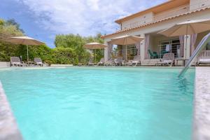 a house with a swimming pool with chairs and umbrellas at Le dune relax con cucina & piscina in San Teodoro