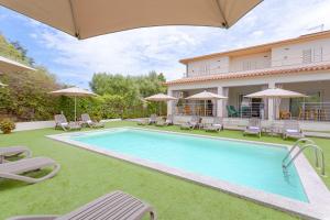 a pool with chairs and umbrellas next to a house at Le dune relax con cucina & piscina in San Teodoro