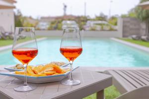 two glasses of wine and chips on a table next to a pool at Le dune relax con cucina & piscina in San Teodoro