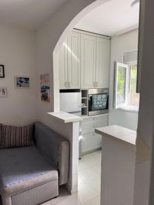 a kitchen with white cabinets and a couch in it at Apartman Dunjićeva in Kotor
