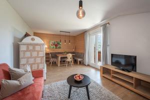 a living room with a couch and a tv and a table at Tirolerhof - panoramic apartments in Natz-Schabs