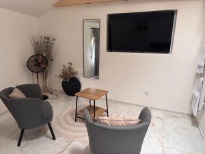 a living room with two chairs and a flat screen tv at Spa Jacuzzi Moon White in Vaudherland