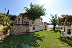 una pequeña casa con un patio con césped y árboles en Thomas Beach Studios, en Paleokastritsa