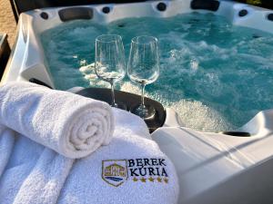 a hot tub with two wine glasses and towels at Berek Kúria in Sonkád +17 photos