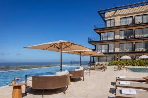 a hotel with chairs and umbrellas next to a pool at Gordonia Zikhron Ya'akov in Zikhron Ya'akov