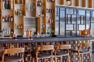 a bar with wooden stools in a room with windows at Gordonia Zikhron Ya'akov in Zikhron Ya'akov