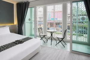 a bedroom with a bed and a table and chairs at Peranakan Boutique Hotel - SHA Plus in Phuket