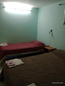 a hotel room with two beds and a light on the wall at Hospedaje DON MANUEL in Paso de Indios