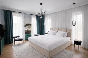 a bedroom with a large white bed and some windows at Berek Kúria in Sonkád