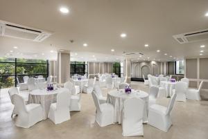a banquet hall with white tables and white chairs at Hotel Explora Calicut by Nova in Kozhikode