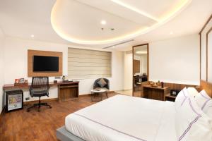 a hotel room with a bed and a desk and a tv at Hotel Explora Calicut by Nova in Kozhikode