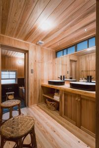 a bathroom with wooden walls and two sinks and a stool at RITA Okawa Hanzakai in Wakatsu