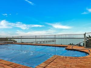 a swimming pool in front of a fence at Toukley Waterfront Apartment with Balcony - Outdoor Pool - Secure Parking - Wi-Fi - By HappyHosts in Toukley