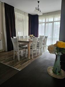 a dining room table with white chairs and a vase with flowers at Бадевски рай-къща Любов in Badewzi +33 photos