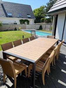 a wooden table and chairs on a patio with a pool at Villa Marius - Piscine - Proche de la plage in Ambleteuse +11 photos