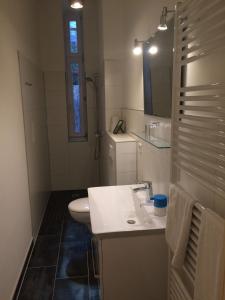ベルリンにあるLodge Berlin - Apartmentsの白いバスルーム(洗面台、トイレ付)
