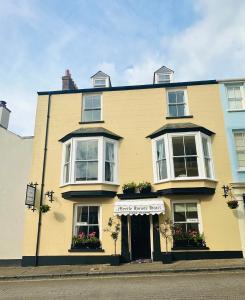 a large yellow building with a store front at Myrtle House Hotel in Tenby
