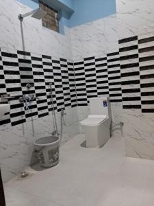 a bathroom with a toilet and black and white stripes at Krishna palace in Pīpalkoti