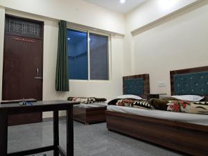 a room with two beds and a table and a window at Krishna palace in Pīpalkoti