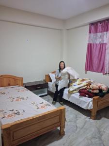a woman sitting on a bed in a room with two beds at Demazong Homestay in Ravangla