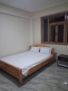 a bedroom with a bed with a wooden frame and a window at Demazong Homestay in Ravangla