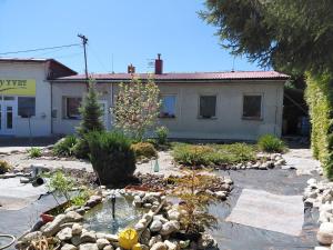 a garden with a pond in front of a building at Apartman YVET in Sučany