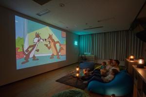 a group of people sitting in a living room watching a presentation at アリビオ伊豆 in Ito