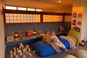 two children sitting on a bed with a book at アリビオ伊豆 in Ito