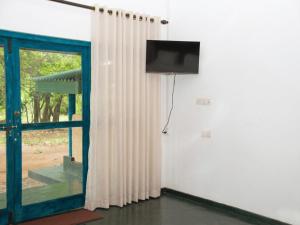 a room with a tv and a window with curtains at Galpothuyaya Eco Lodge Kandalama in Dambulla
