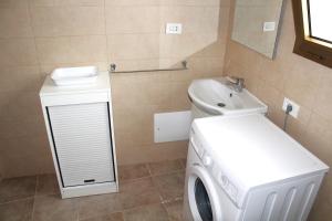 ein Badezimmer mit Waschmaschine und Waschbecken in der Unterkunft bilo giuggianello by salentolimit in Torre Lapillo + 1 Foto
