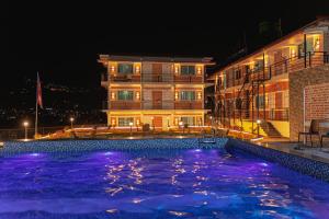 a swimming pool in front of a building at night at Shikali Resort in Pātan