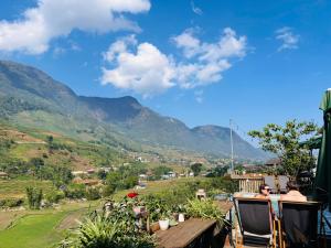 two people sitting on a deck with mountains in the background at Lee Eco House Sapa in Sapa