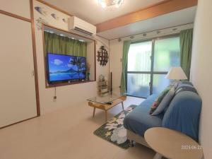 a living room with a blue couch and a television at Green Hights Residence-101 in Naha