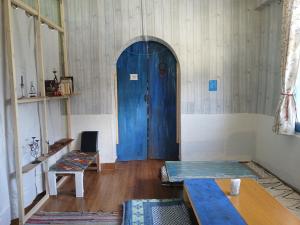a room with a blue door and a wooden floor at Dormitory Hatago in Vashisht