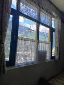 a window with a view of a mountain at Dormitory Hatago in Vashisht +12 photos